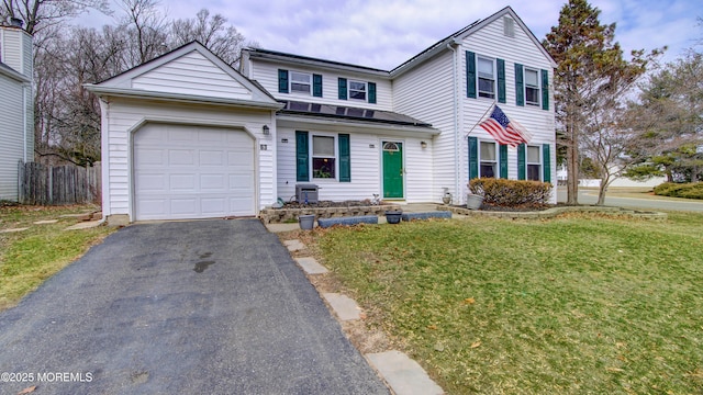 traditional-style home with an attached garage, driveway, fence, and a front lawn