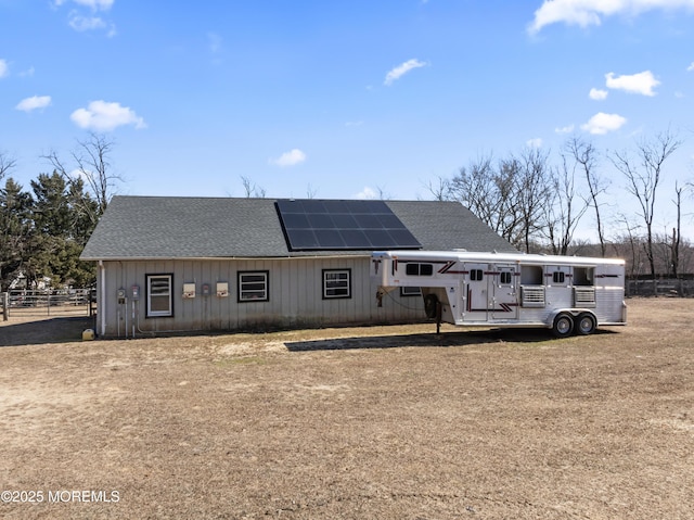 view of front of home with a shingled roof, fence, and solar panels