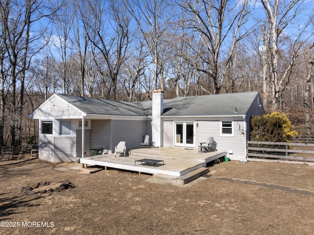 back of property featuring fence, a chimney, and a wooden deck