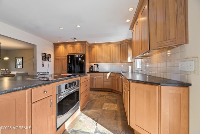 kitchen featuring tasteful backsplash, dark countertops, stone tile flooring, recessed lighting, and black appliances