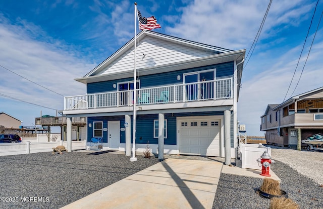 view of front of house featuring a garage, concrete driveway, covered porch, and fence