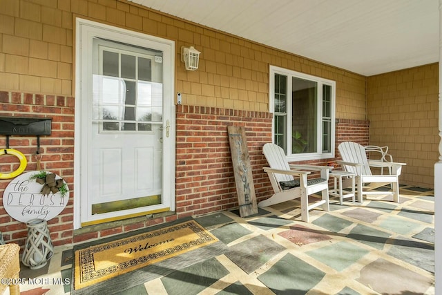 doorway to property with a porch and brick siding