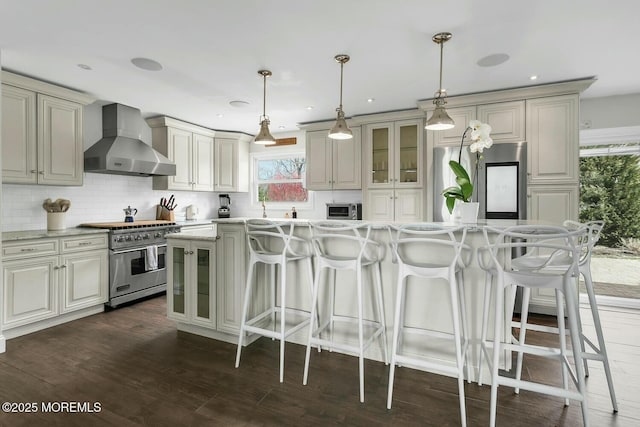 kitchen featuring stainless steel appliances, decorative backsplash, dark wood-type flooring, glass insert cabinets, and wall chimney exhaust hood