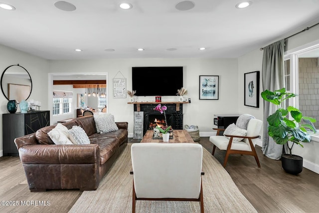 living room with recessed lighting, baseboards, a brick fireplace, and wood finished floors