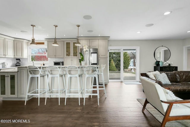 kitchen featuring decorative light fixtures, a kitchen breakfast bar, dark wood-style floors, light countertops, and glass insert cabinets