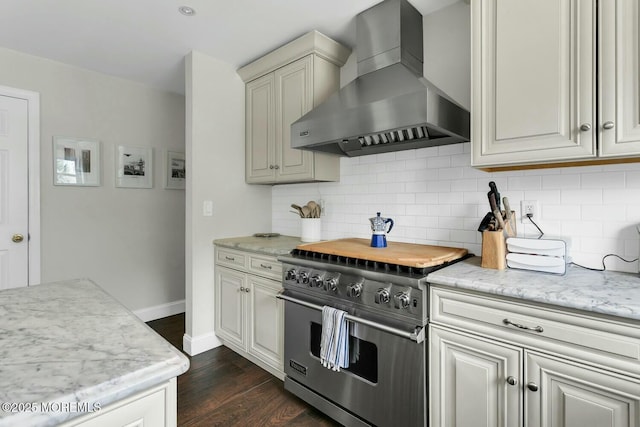 kitchen with dark wood-type flooring, high end stainless steel range oven, tasteful backsplash, wall chimney exhaust hood, and baseboards