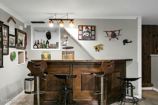 bar featuring baseboards, a dry bar, tile patterned flooring, and ornamental molding