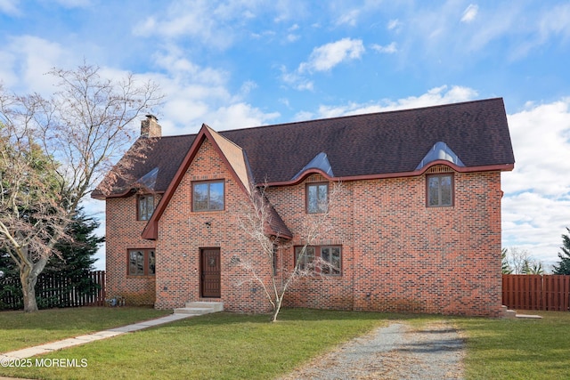 view of front of house featuring a front lawn, fence, roof with shingles, brick siding, and a chimney