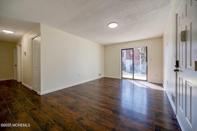 spare room with dark wood finished floors, visible vents, and baseboards