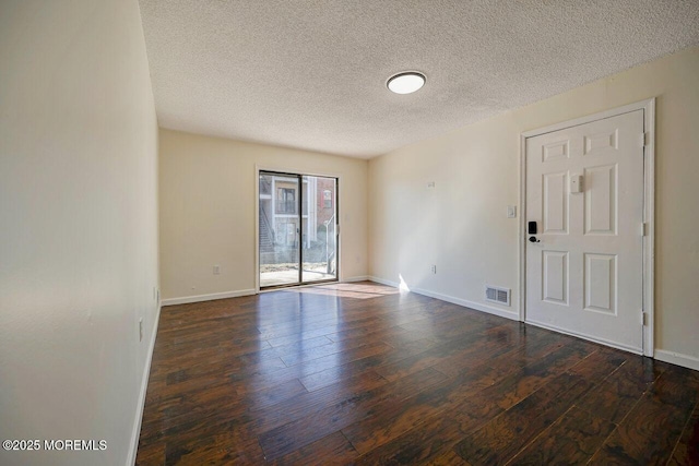 spare room featuring wood-type flooring, visible vents, a textured ceiling, and baseboards