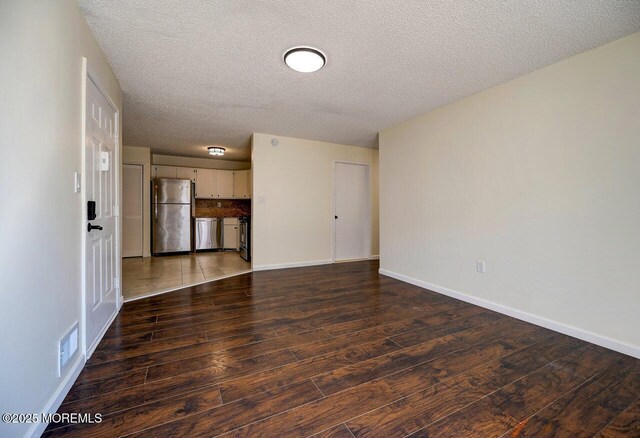 empty room with hardwood / wood-style flooring, baseboards, and a textured ceiling