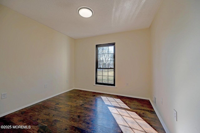 spare room featuring a textured ceiling, wood finished floors, and baseboards