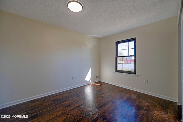 unfurnished room with a textured ceiling, dark wood-type flooring, visible vents, and baseboards