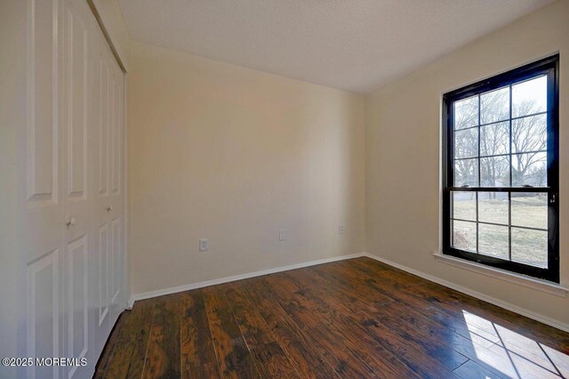 unfurnished room with dark wood-style floors and baseboards