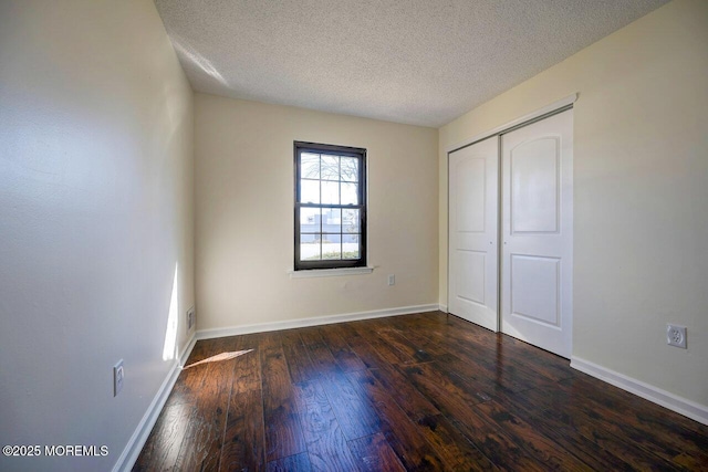 unfurnished bedroom featuring dark wood-style floors, a textured ceiling, and baseboards