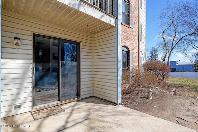 entrance to property with a balcony, crawl space, a patio, and brick siding