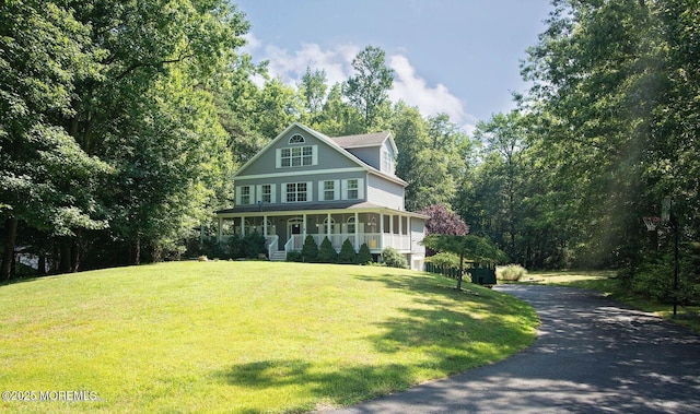 view of front of property with a front yard, covered porch, and driveway