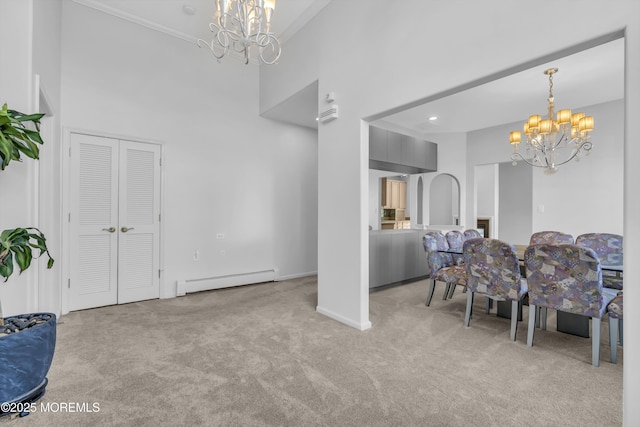 carpeted dining room featuring a baseboard heating unit, a towering ceiling, and an inviting chandelier