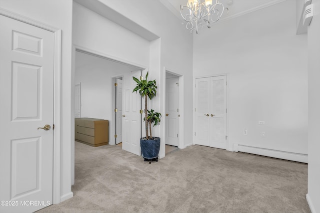 interior space featuring a chandelier, a baseboard radiator, a towering ceiling, and carpet