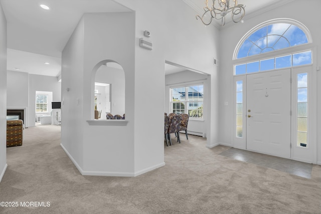 carpeted entryway featuring a towering ceiling, plenty of natural light, baseboards, and a baseboard radiator