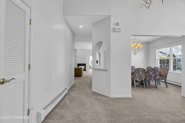 hallway featuring baseboards, carpet floors, baseboard heating, and a notable chandelier