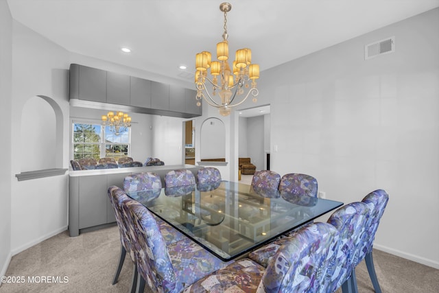 dining area featuring light carpet, visible vents, arched walkways, and a notable chandelier