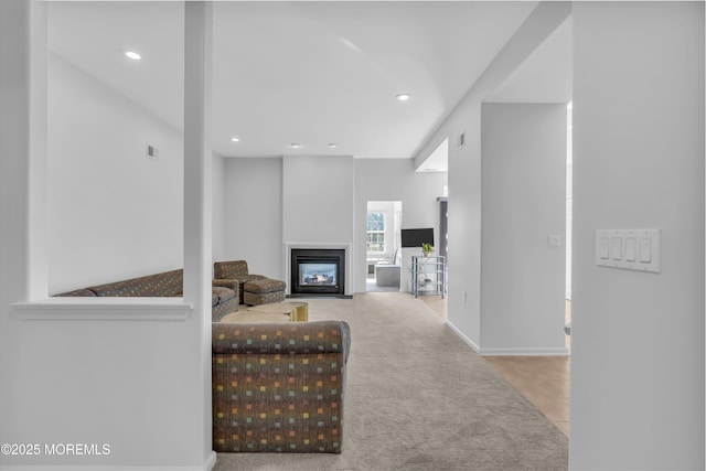 carpeted living room featuring a glass covered fireplace, visible vents, and recessed lighting