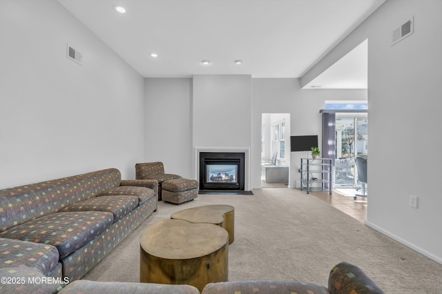 living area featuring carpet, a fireplace with flush hearth, visible vents, and recessed lighting