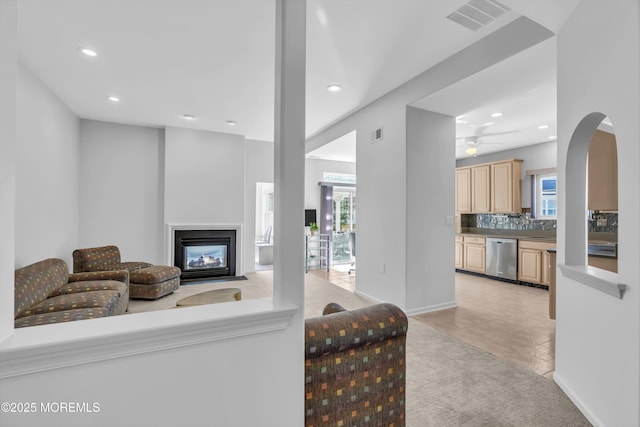 living room with recessed lighting, visible vents, a wealth of natural light, and a multi sided fireplace