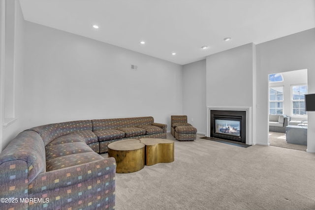 living room featuring a fireplace with flush hearth, carpet, visible vents, and recessed lighting