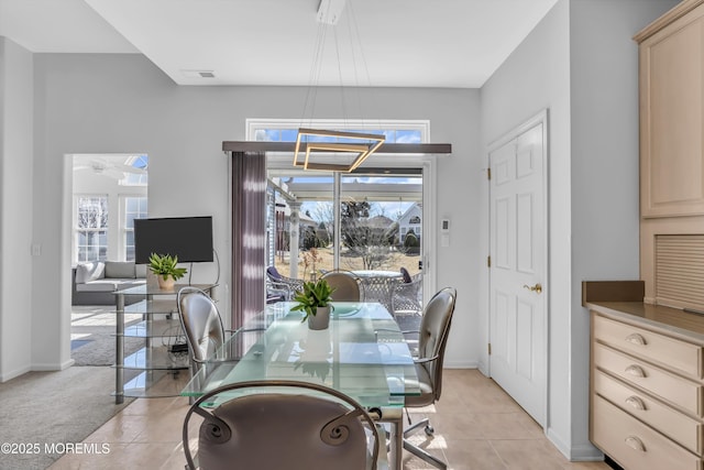 dining room featuring a healthy amount of sunlight, baseboards, light colored carpet, and light tile patterned flooring