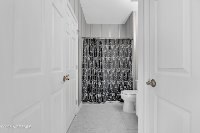 bathroom with curtained shower, tile patterned flooring, and toilet