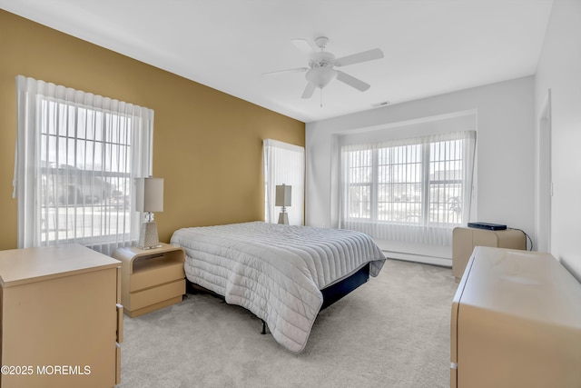 bedroom featuring light colored carpet, a baseboard radiator, multiple windows, and ceiling fan