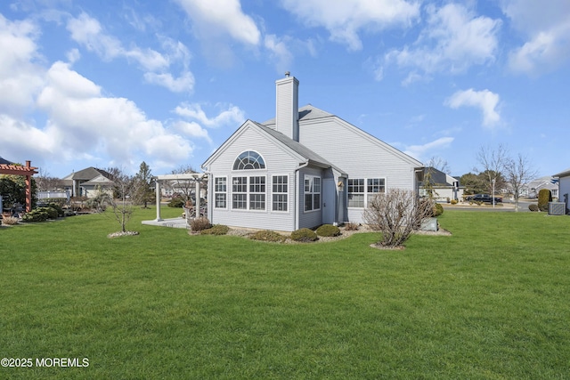 rear view of house featuring a chimney and a yard