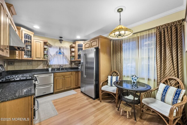 kitchen featuring decorative backsplash, light wood-style flooring, appliances with stainless steel finishes, crown molding, and a sink