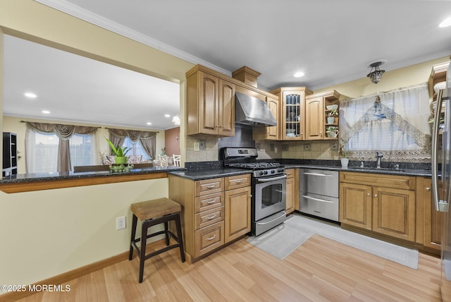 kitchen featuring crown molding, backsplash, a sink, wall chimney range hood, and stainless steel gas range