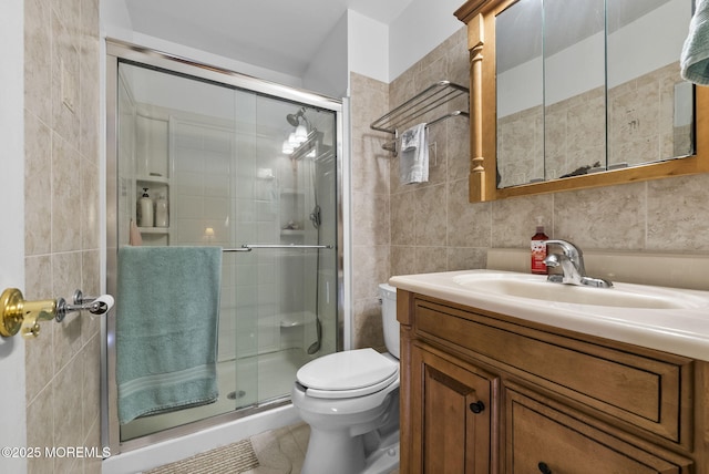 bathroom with toilet, a stall shower, tile walls, and vanity