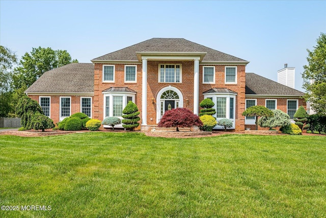 1 Christie Ln, Freehold, NJ 07728 - neoclassical / greek revival house with a front lawn, a chimney, brick siding, and a shingled roof