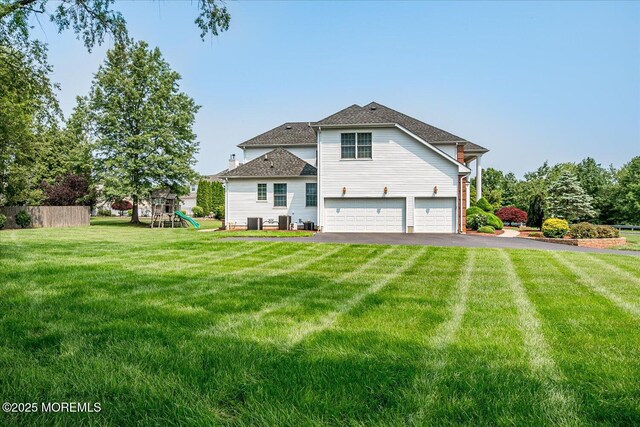 1 Christie Ln, Freehold, NJ 07728 - back of property featuring an attached garage, driveway, a playground, and a shingled roof