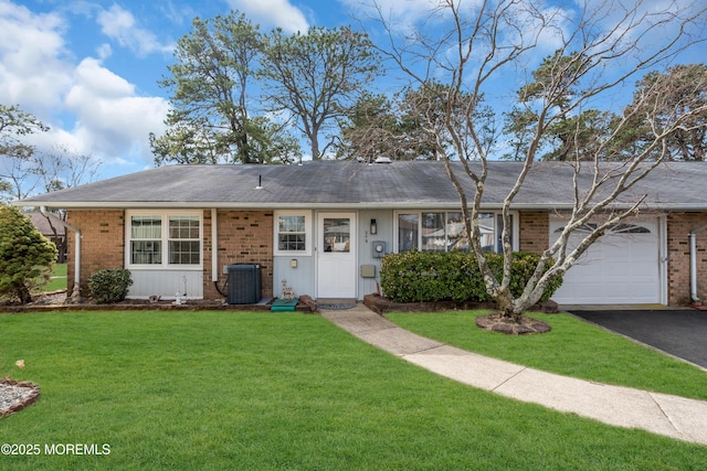 ranch-style home featuring an attached garage, a front yard, aphalt driveway, and brick siding