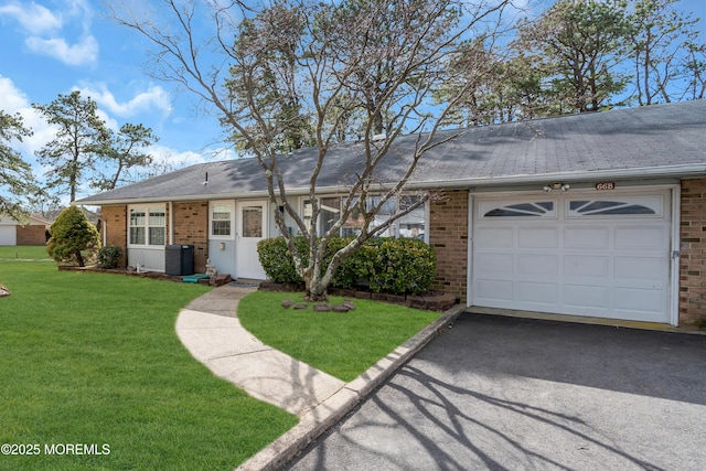 ranch-style home featuring driveway, a garage, cooling unit, a front lawn, and brick siding