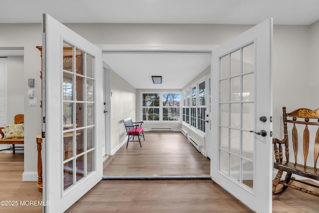 interior space with a baseboard radiator, baseboards, and wood finished floors