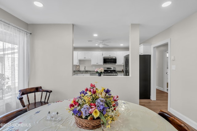 dining room featuring baseboards, wood finished floors, and recessed lighting