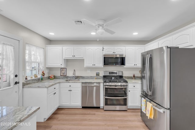 kitchen featuring visible vents, stainless steel appliances, light wood-style floors, white cabinetry, and a sink