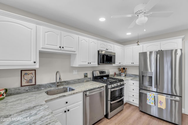 kitchen with appliances with stainless steel finishes, a sink, and white cabinetry