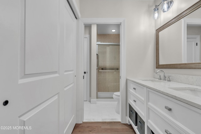 bathroom with double vanity, a sink, toilet, and a shower stall