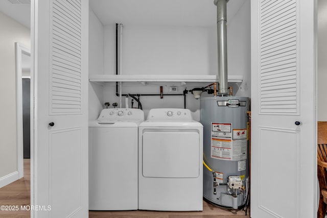 laundry room with wood finished floors, gas water heater, washing machine and dryer, and laundry area