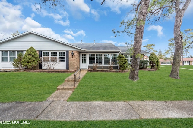 ranch-style home with a sunroom, a front lawn, and brick siding