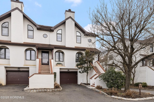 view of property with aphalt driveway, stairway, and stucco siding