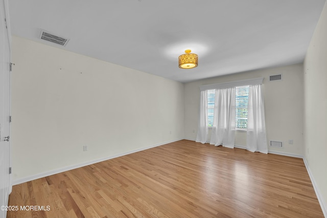 spare room with light wood-style floors, visible vents, and baseboards